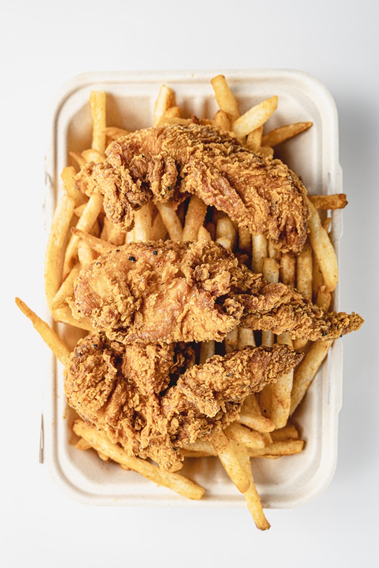 Three jumbo chicken tenders on a bed of cajun fries in a takeaway box