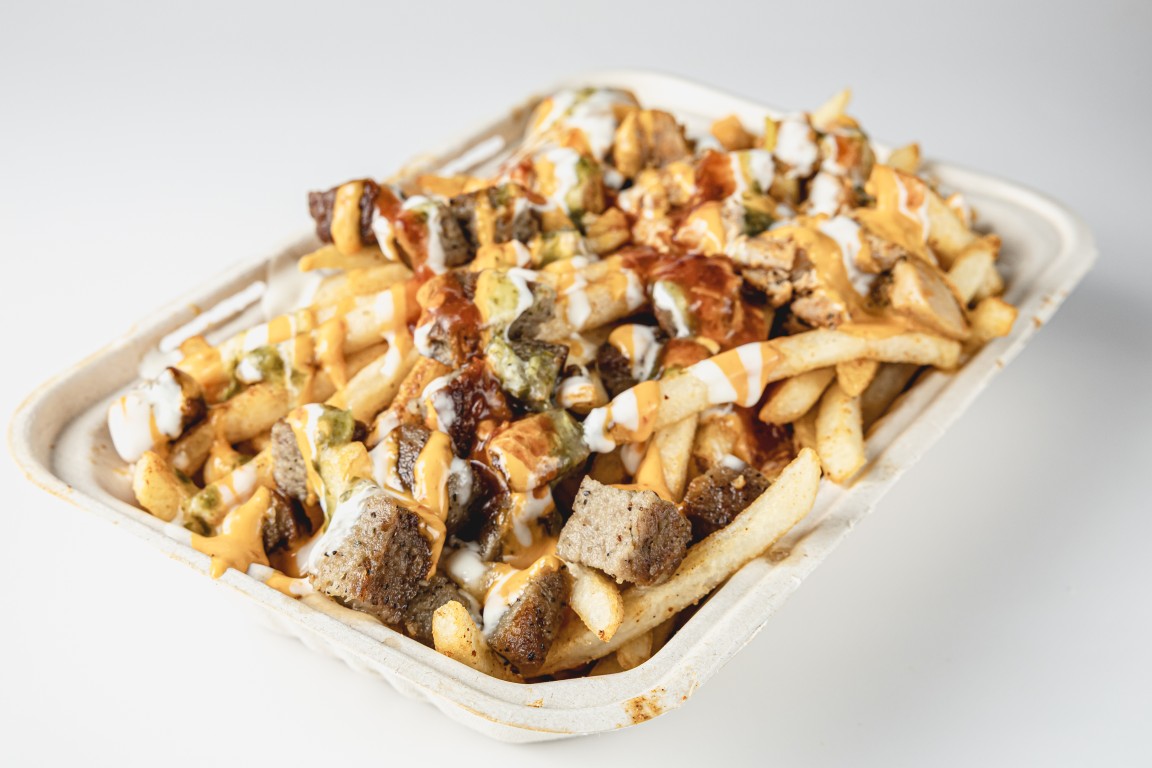 Loaded fries with gyro meat, sauces and jalapeños in a takeaway box